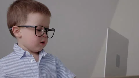 Funny child boy glasses using laptop, looking to camera, businessman smart baby Stock Footage 195955157