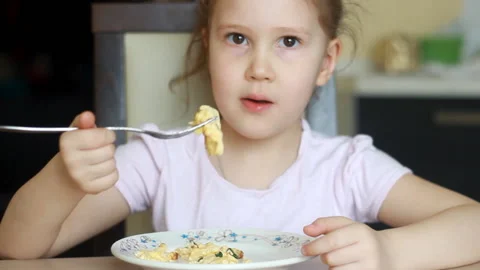Funny child eats omelet in several pieces close up. Baby girl is hungry and has Stock Footage 139268949