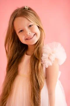 Funny child girl 7-8 year old with long blonde hair posing over pink backgrou Stock Photos