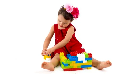 Funny child girl playing with construction set over white background Stock Photos