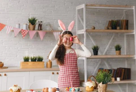 A funny child holds Easter eggs near his eyes. A happy family is preparing fo Stock Photos