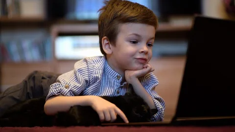 Funny child with kitten using a laptop at home. Stock Footage 129337645