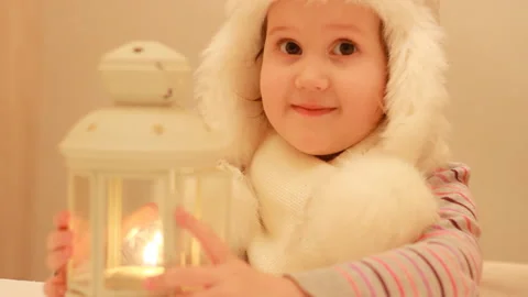 A funny child looking a candle flame in a lantern. A sweet girl makes a wish and Stock Footage 85624207