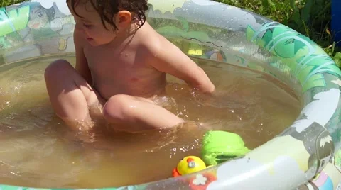 Funny child playing in a sandbox in a children's inflatable pool. Stock Footage 68604174