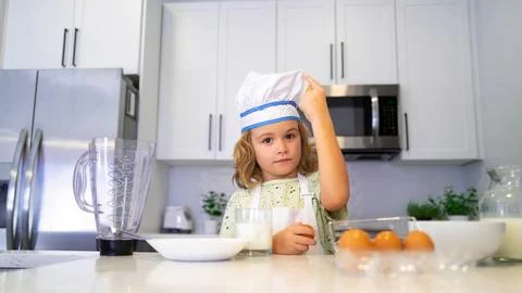 Funny child stand at kitchen table have fun baking, doing bakery preparing food Stock Photos