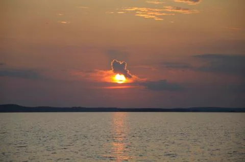 Funny cloud sitting on sun during sunset Stock Photos