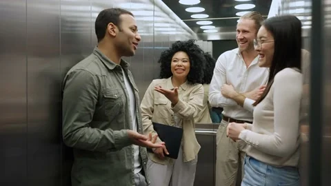 Funny colleagues discussing work project and riding in elevator in office Stock Footage 238373718