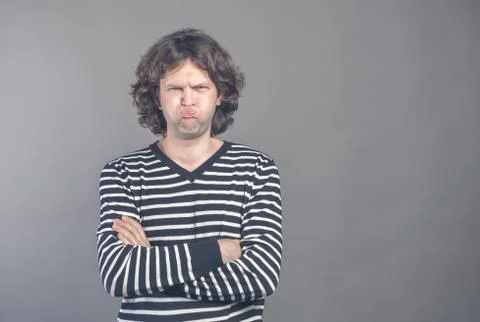 Funny comic man pouts lips and cheeks makes angry grimace, foolishes after al Stock Photos
