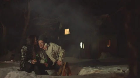 Funny couple by the fire with beer. Video stock 106459085