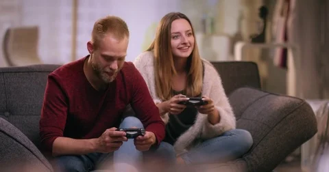 Funny couple sitting on couch playing video games Video stock 77409590