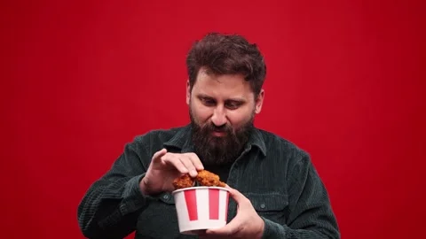 Funny crazy face. Bearded man eating fried chicken with hot chilli sauce against Stock Footage 242703839