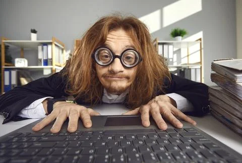 Funny crazy looking nerd in thick lens glasses sitting in office and using 스톡 사진