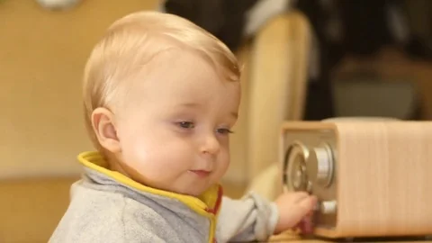 Funny cute 9-10 months old baby boy switch on and play with radio Stock Footage 82460005