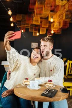 Funny cute couple making memorable photo sitting in cafe Stock Photos
