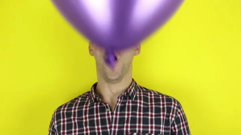 A funny, cute guy is actively playing with a purple balloon. Stock Footage 127645282
