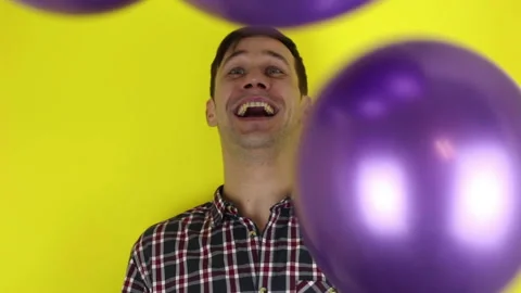 A funny, cute guy is actively playing with a purple balloon. Stock Footage 127645695