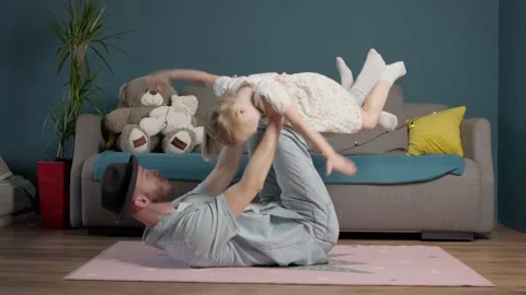 Funny dad. cheerful dad plays with his daughter on the floor. cheerful family in Stock Footage 165296125