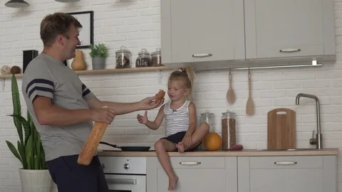 Funny dad feeds his little daughter bread in the morning in the kitchen Stock Footage 112334032