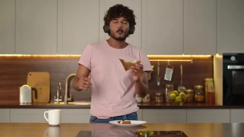 Funny dancing guy listen headphone while eating sandwich with meat. Relaxed Stock Footage 259236299