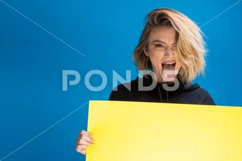 Funny dark blonde pulling hertongue out while holding an advertising cardboard Stock Photos