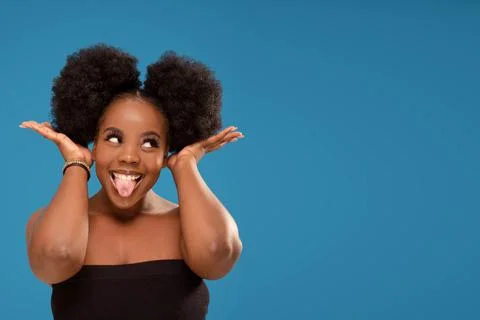 Funny dark-skinned young afro woman sticking tongue and making faces to the c 스톡 사진