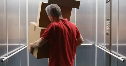Funny delivery man dropping parcels in the elevator Stock Footage 308916385