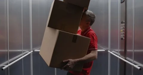 Funny delivery man dropping parcels in the elevator 스톡 동영상 308916387