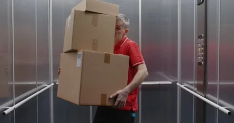 Funny delivery man dropping parcels in the elevator Stock Footage 308916420