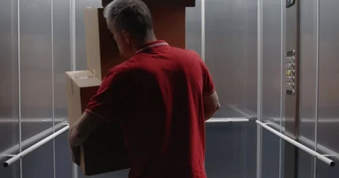 Funny delivery man dropping parcels in the elevator Stock Footage 308916432