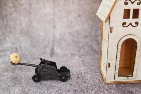Funny diorama of a catapult while pulling a peanut on a wooden house Stock-Fotos