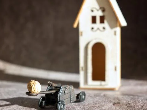Funny diorama of a catapult while pulling a peanut on a wooden house Stock Photos