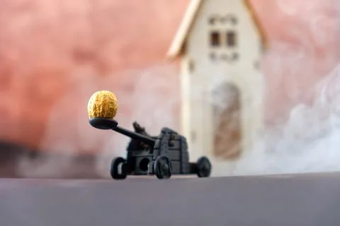 Funny diorama of a catapult while pulling a peanut on a wooden house Stock Photos