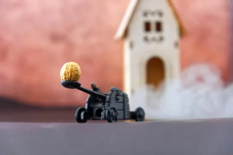 Funny diorama of a catapult while pulling a peanut on a wooden house Stock-Fotos