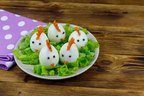 Funny easter breakfast with boiled eggs as chicks on wooden table Stock Photos