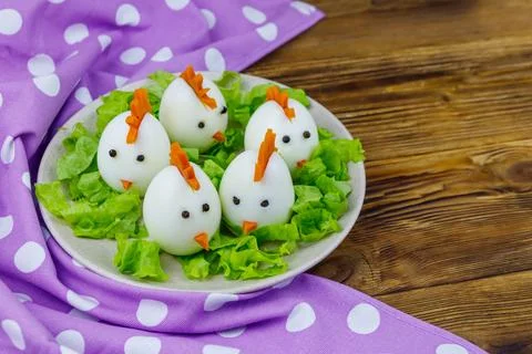 Funny easter breakfast with boiled eggs as chicks on wooden table Stock Photos