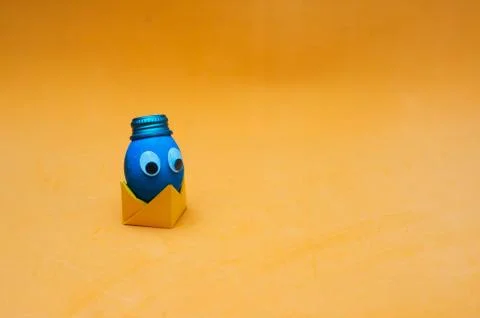 Funny easter egg with googly eyes in a hat on paper origami stand. Easter con Stock Photos