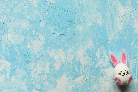 Funny Easter egg on light blue background in the right lower corner. Copy space. Stock Photos