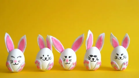 Funny Easter eggs decorated as bunnies change places on the yellow background. Stock Footage 149703235