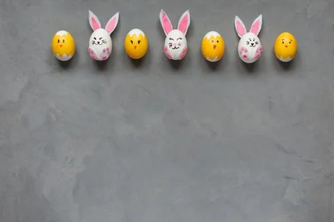 Funny Easter eggs decorated as bunnies and chicks laying on gray background in Stock Photos