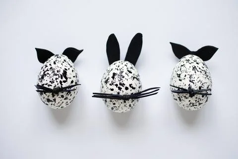 Funny Easter eggs decorated as spotted bunnies with black ears and whiskers on Stock Photos