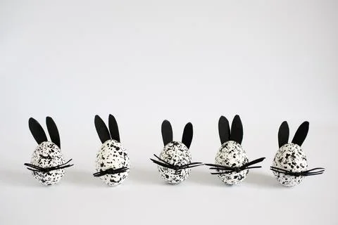 Funny Easter eggs decorated as spotted black and white bunnies on the white Stock Photos