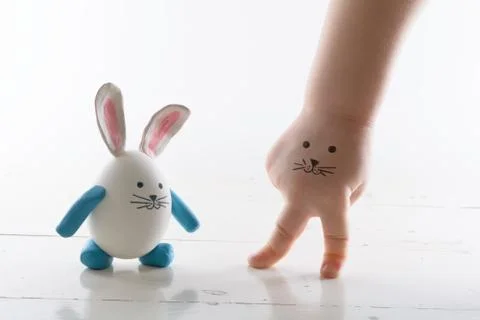 Funny easter rabbit and child hand with cute face. Little easter friends. V.. Stock Photos