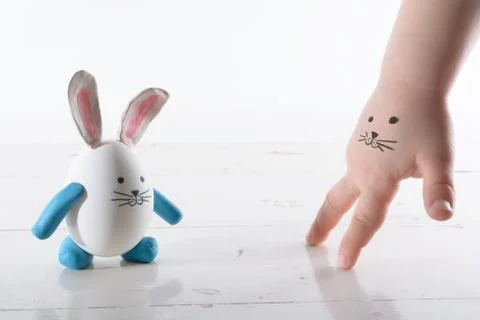 Funny easter rabbit and child hand with cute face. Face painted on a child'.. Stock Photos