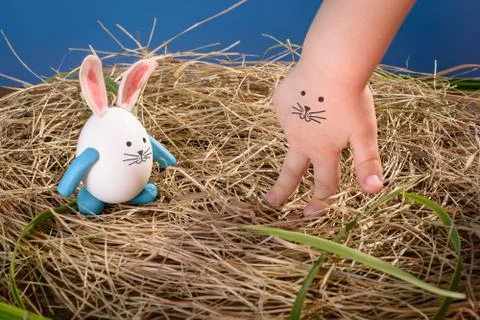 Funny easter rabbit and child hand with cute face Stock Photos