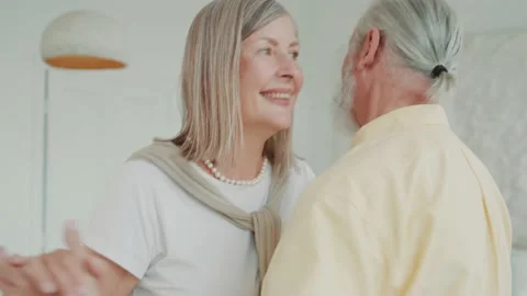 Funny elderly old couple dancing in the living room. A lovely husband holds the Vídeos de archivo 224532054