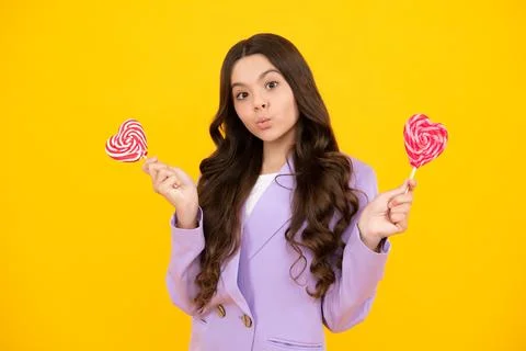 Funny face. Cool teen child with lollipop over yellow isolated background. Sweet Stock Photos