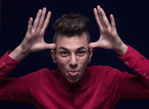 Funny face, funny expression, one teenager boy, tongue out, hands next to fac Stock Photos