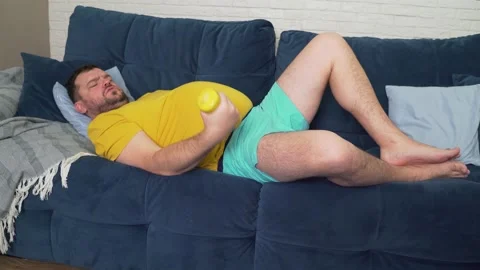 Funny fat man is actively engaged in fitness with yellow small dumbbells Stock Footage 169083761