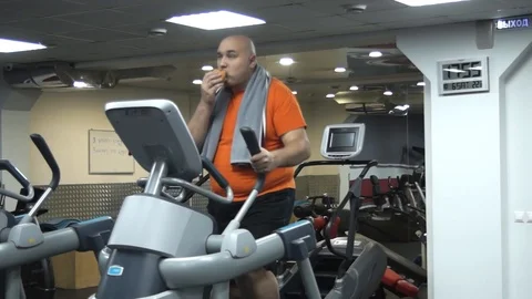 Funny fat man doing exercises on the ellipsoid in gym 스톡 동영상 96405317