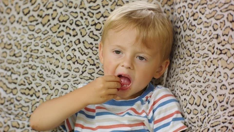 A funny four-year-old boy enjoys eating raspberries on a village swing. Stock Footage 129639141